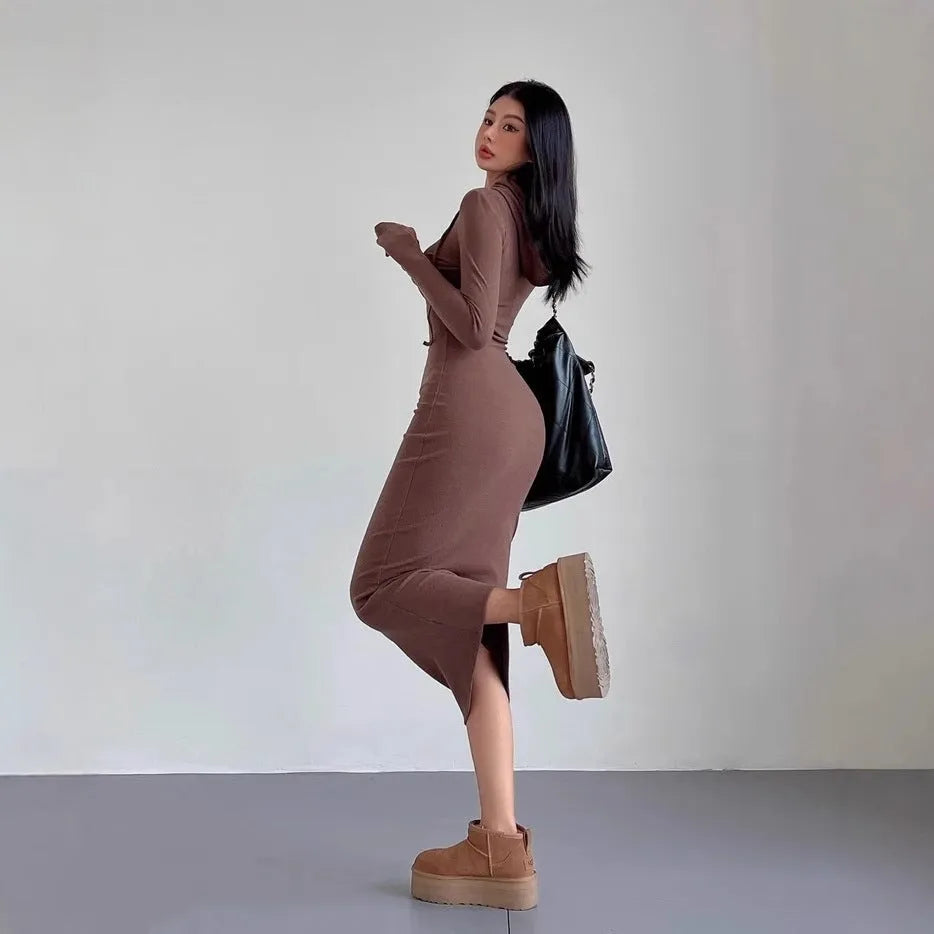 A woman modelling a grey hooded long sleeve sheath dress with a high waist.