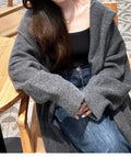 Women's long hooded knitted cardigan in oatmeal colour, showing below-knee length and loose fit.