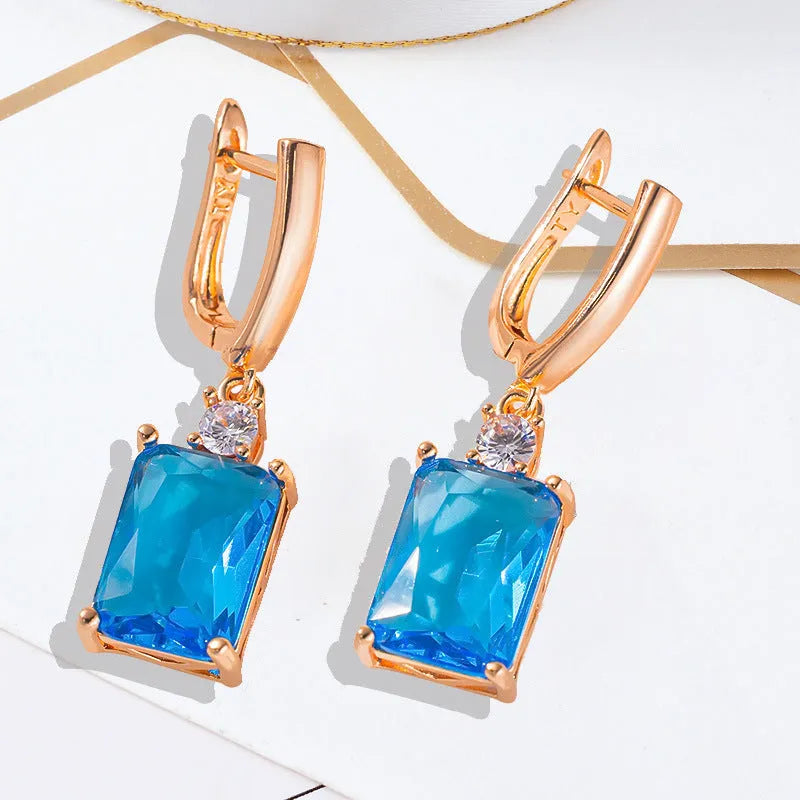 A pair of square-shaped gold and silver electroplated copper earrings showing front view.