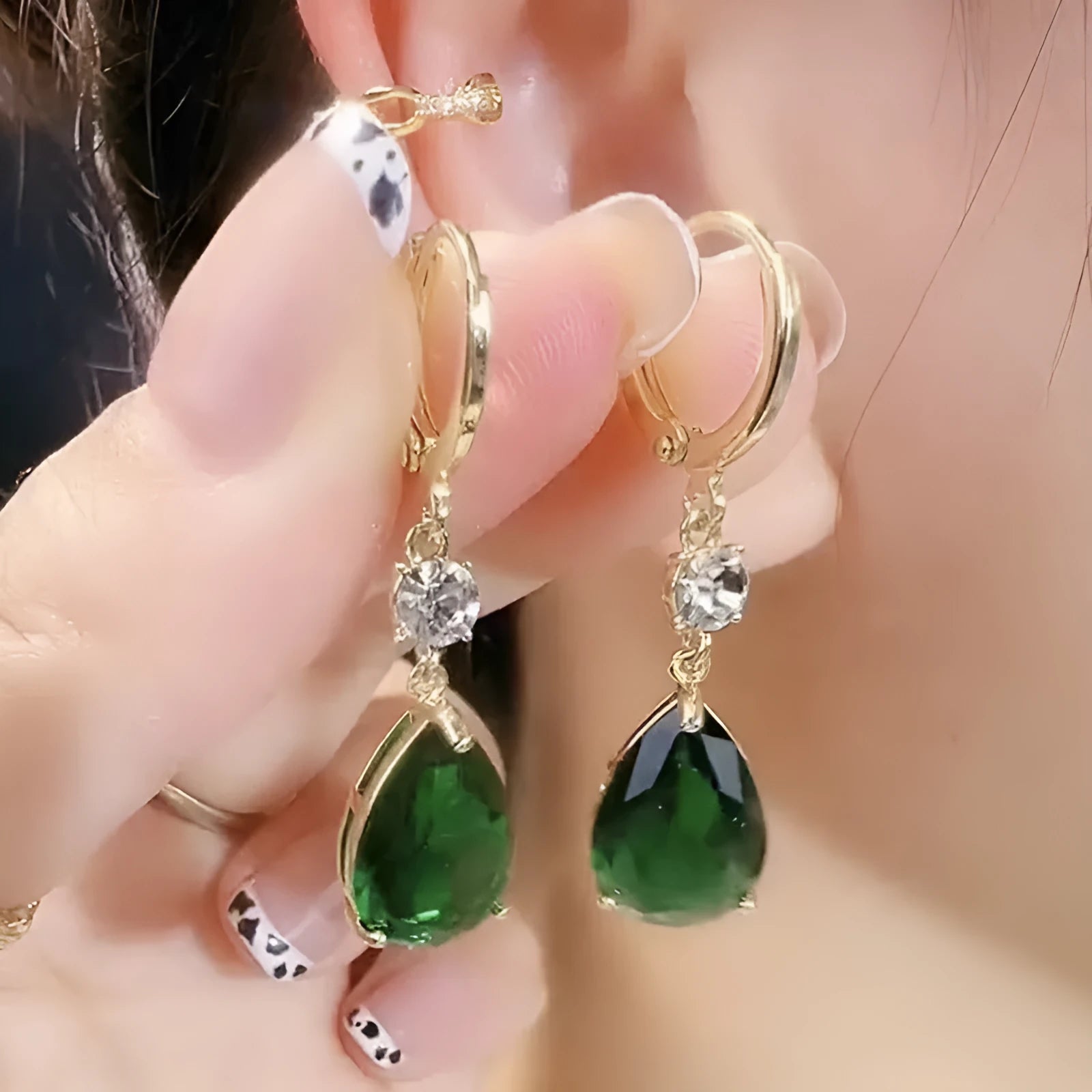 A pair of green geometric teardrop-shaped alloy earrings on a plain background.