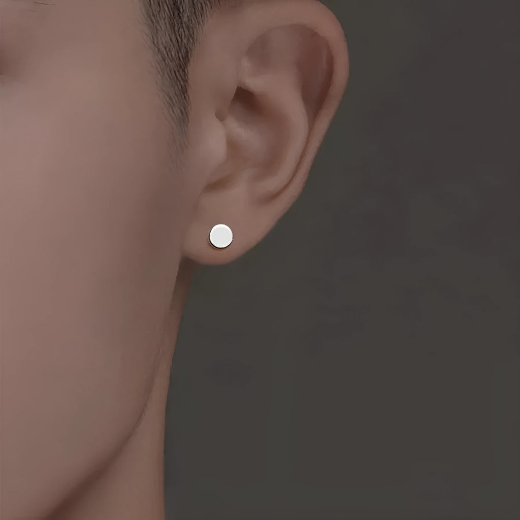 A pair of round, flat S999 sterling silver bone stud earrings on a plain background.