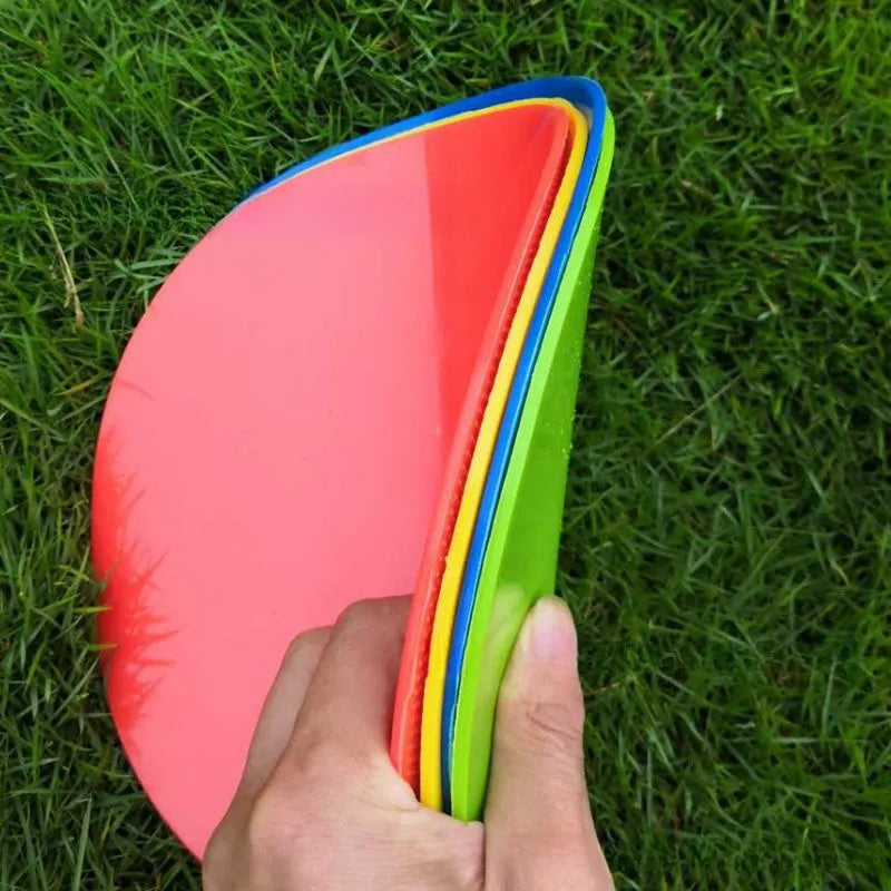 Flat yellow TPE football training landmark pad disc on grass, 23 cm in diameter.