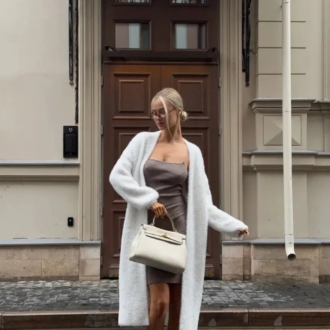 White loose-fit knitted cardigan jacket with long sleeves and an extended length.