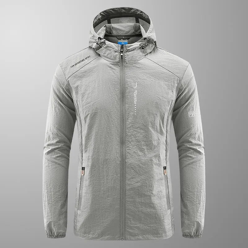 Man wearing a lightweight grey hooded nylon summer jacket outdoors.