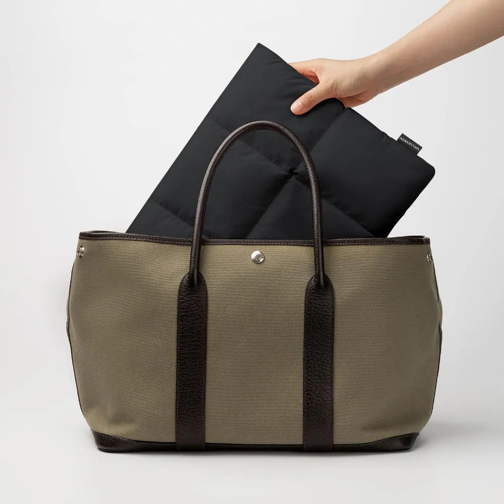 Soft fluffy polyester laptop sleeve in black and khaki colours on a table, showing sewing thread detail and size options.