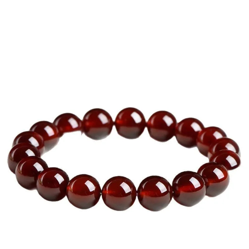 Natural orange red garnet ball bead bracelet with ruyi charms on a wrist.