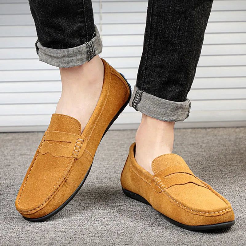 Men's solid colour suede loafers with a round toe and flat rubber sole on a neutral background.