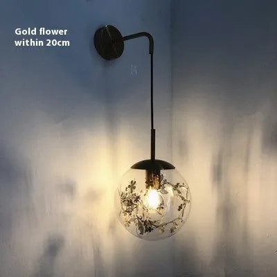 Small modern glass wall lamp in golden flower or silver flower finish for bedside lighting.