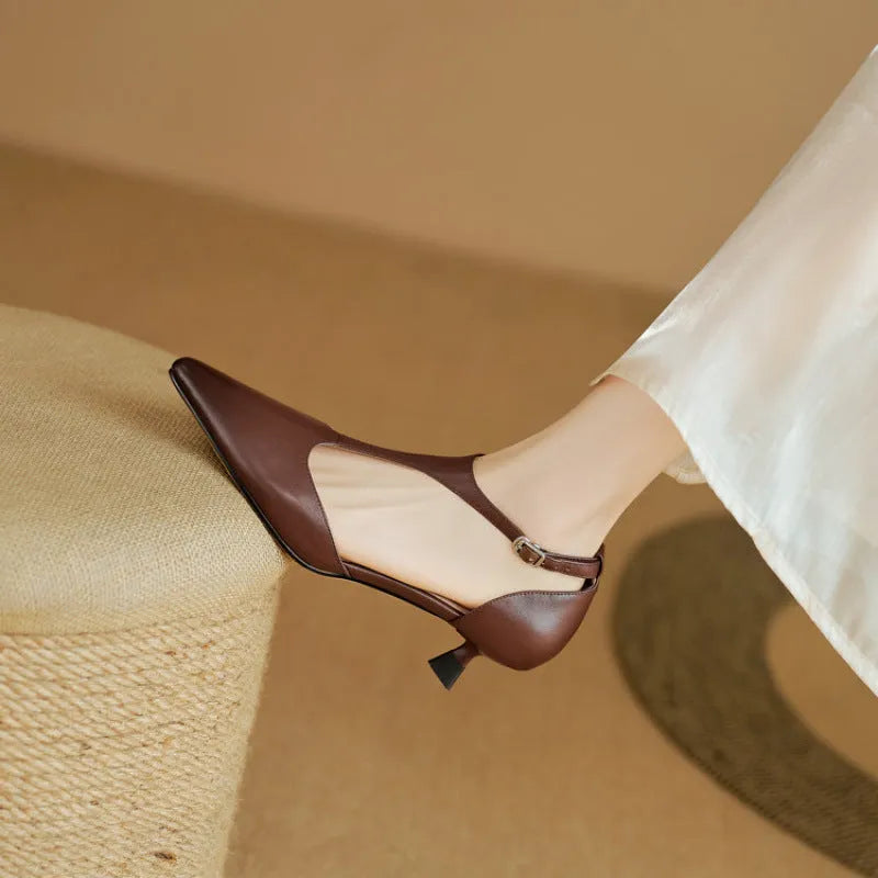 A pair of brown cowhide leather women's high heels with a pointed toe on a plain background.