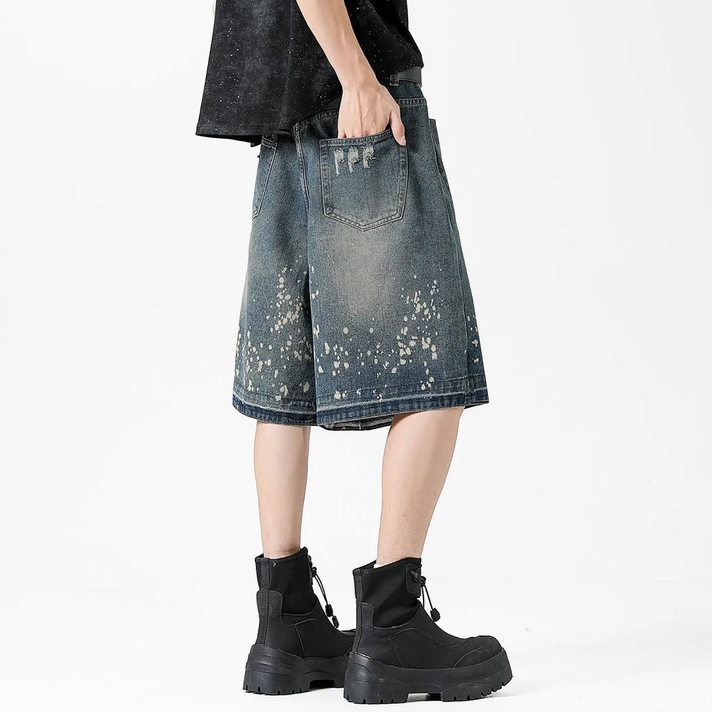 Man wearing retro blue washed denim shorts with ripped details and a straight-leg cut.