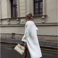 White loose-fit knitted cardigan jacket with long sleeves and an extended length.