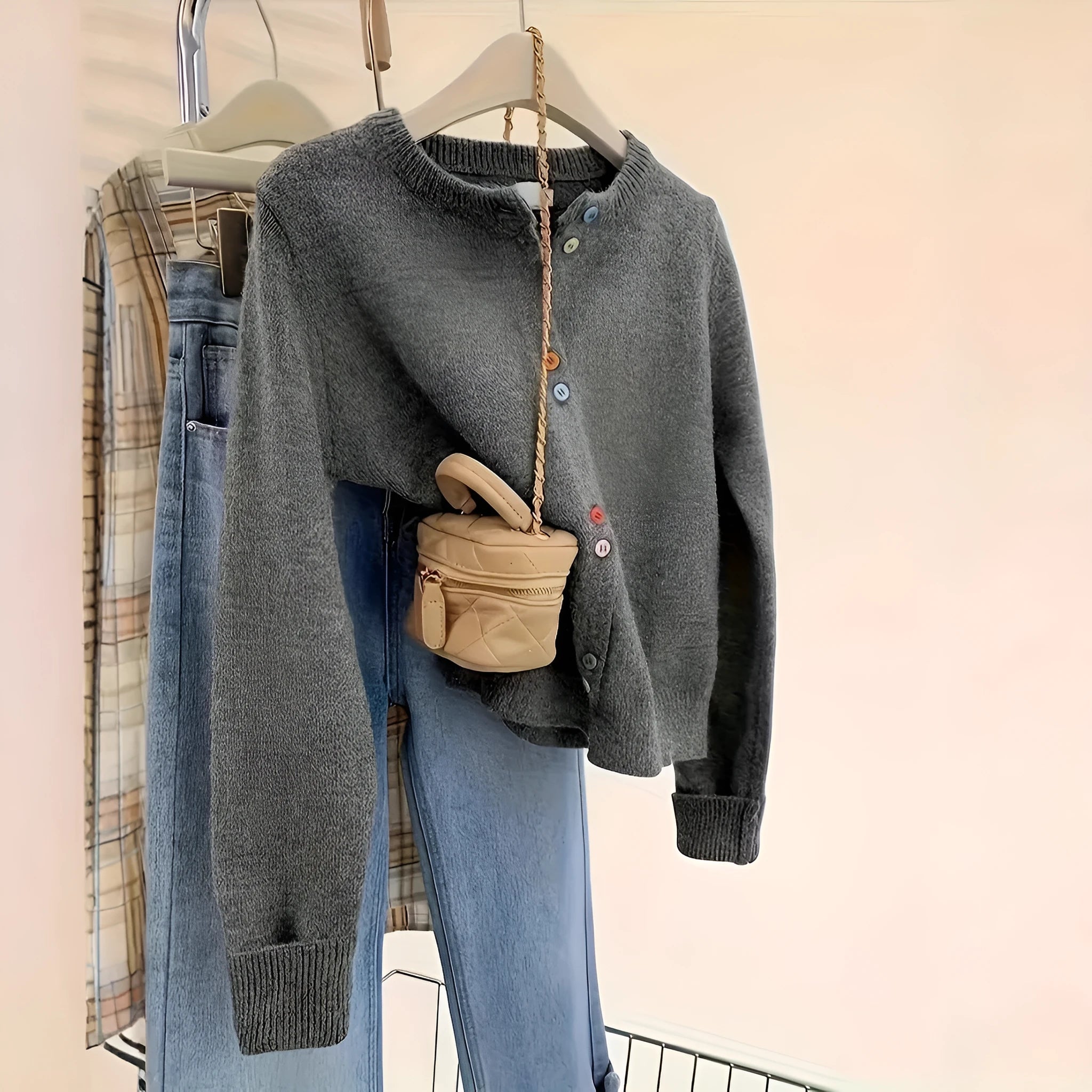 Dark grey women's button-front cardigan sweater on a hanger, showing long sleeves and regular length.