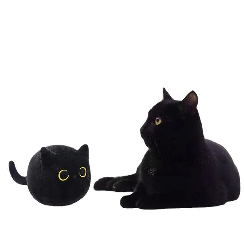 Fluffy black cat stuffed toy with embroidered eyes and whiskers on a grey background.