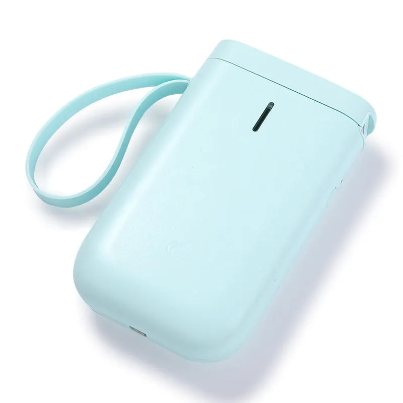 D11 compact white Bluetooth thermal label printer with USB cable and roll of label paper on a desk.