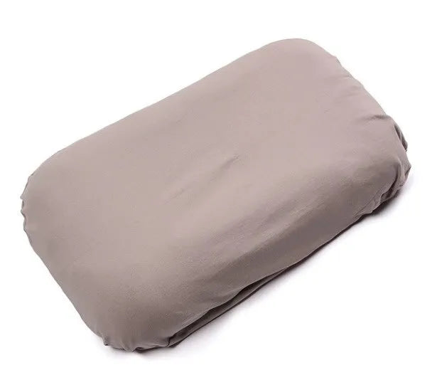 Beige portable cotton baby nest crib for newborn infants on a bed.