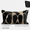 Black and gold abstract patterned square cushion on a grey sofa