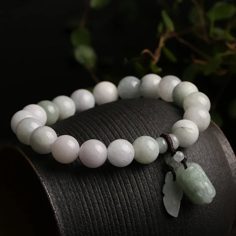 Natural green jade bracelet with a geometric hanging pendant showing choice of symbolic designs.