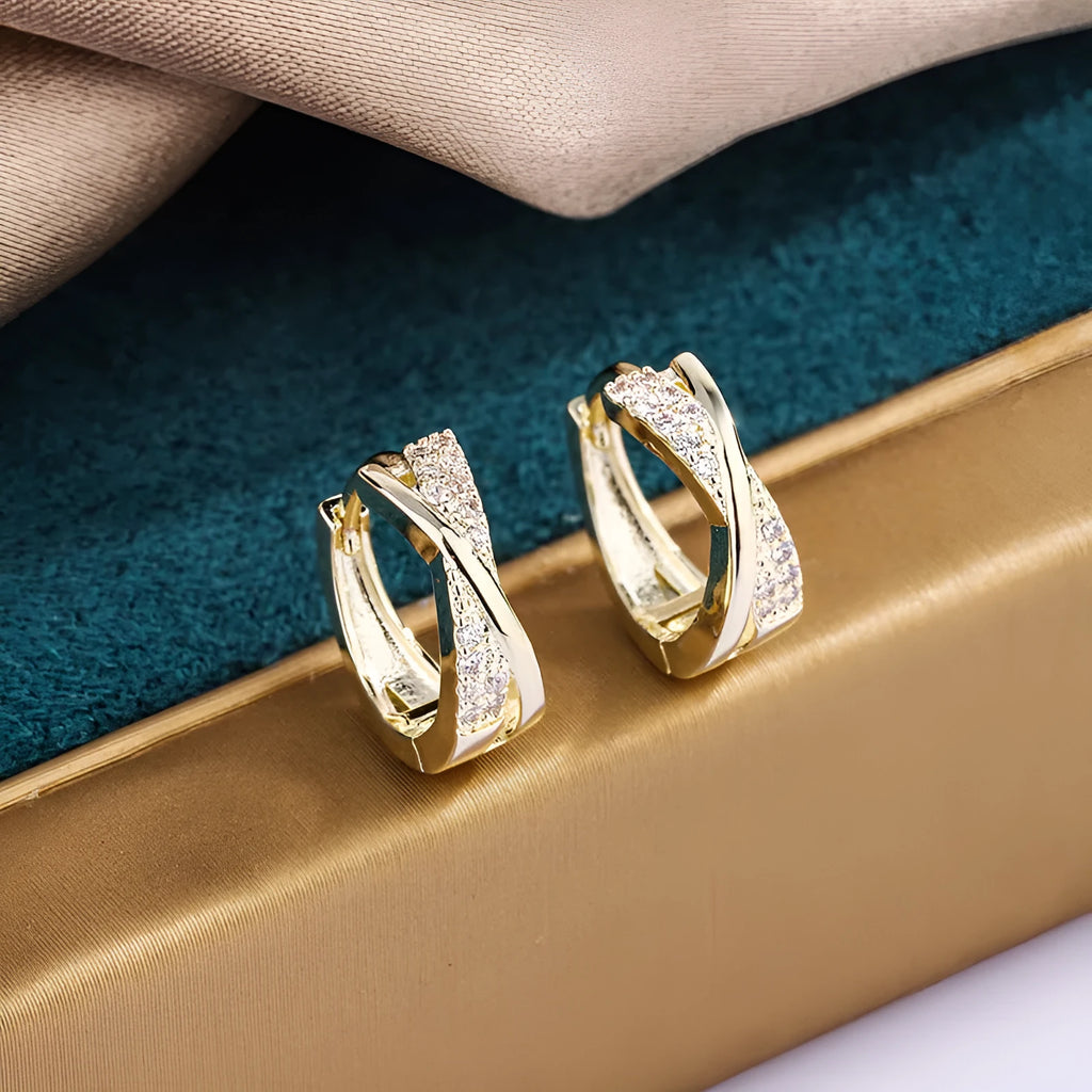 A pair of geometric stud earrings with zircon detail and 14K yellow gold plating on a copper base.