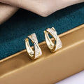 A pair of geometric stud earrings with zircon detail and 14K yellow gold plating on a copper base.