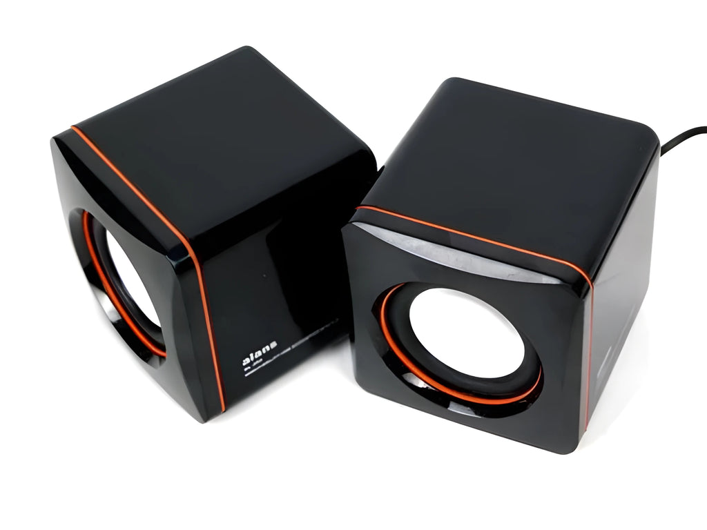 Small black square USB computer speaker on a desk next to a laptop.