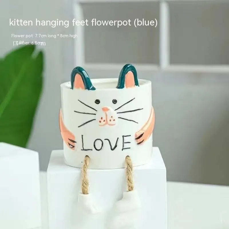 Ceramic cartoon-style hanging foot flowerpot for succulent plants on a desktop.