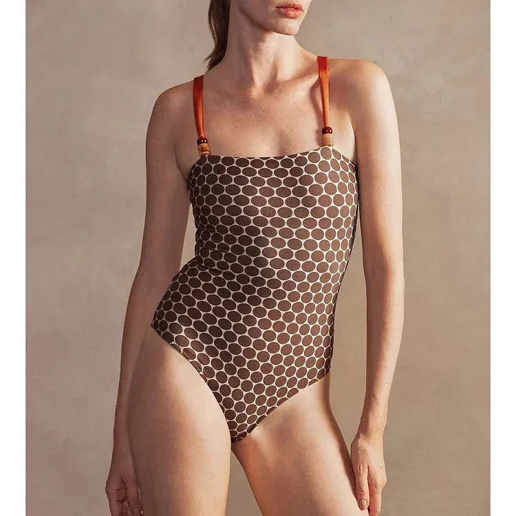Women's dotted one-piece swimsuit with a matching wrap skirt laid flat.