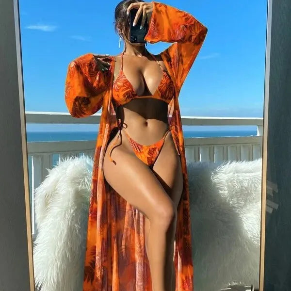 Women's blue long sleeve bikini top and banded briefs with a matching robe laid flat.