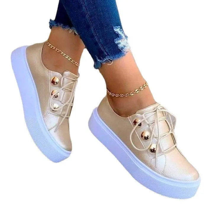 Women's white lace-up flats sneakers with rivet decoration on the side, showing round toe and casual style.