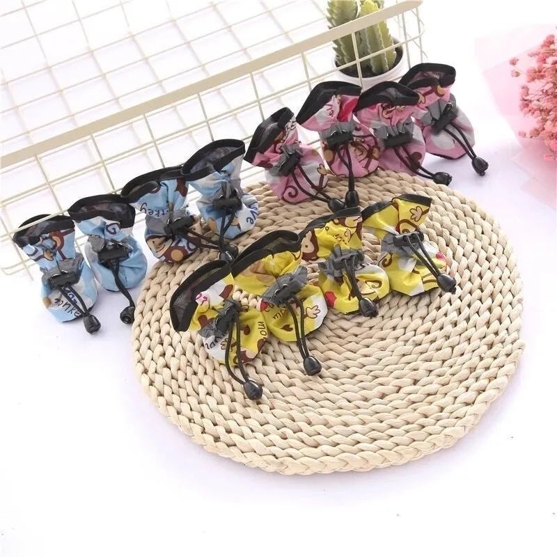 Set of four cloth dog shoes with soft soles in assorted colours on a neutral background
