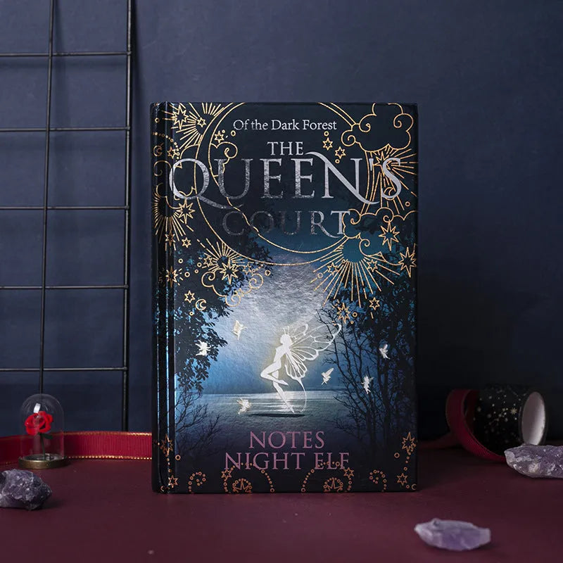 Blue luminous hardcover A5 notebook lying open on a desk, showing full-colour illustrated pages.