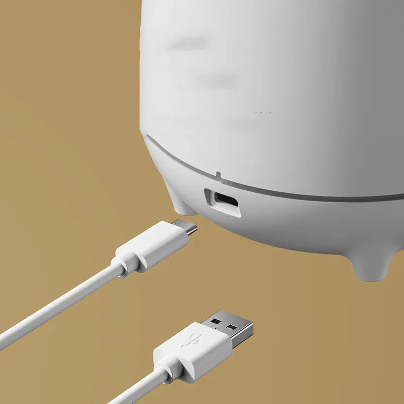 White volcano-shaped ultrasonic humidifier with USB cable on wooden table