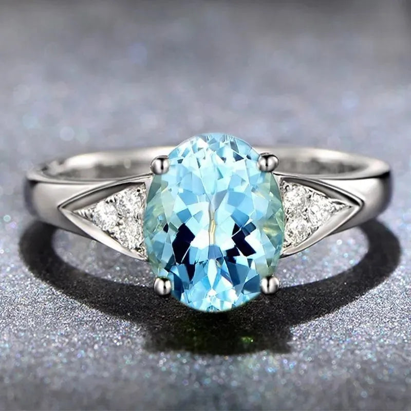 Women's court style zircon ring with heart pattern and blue stone.