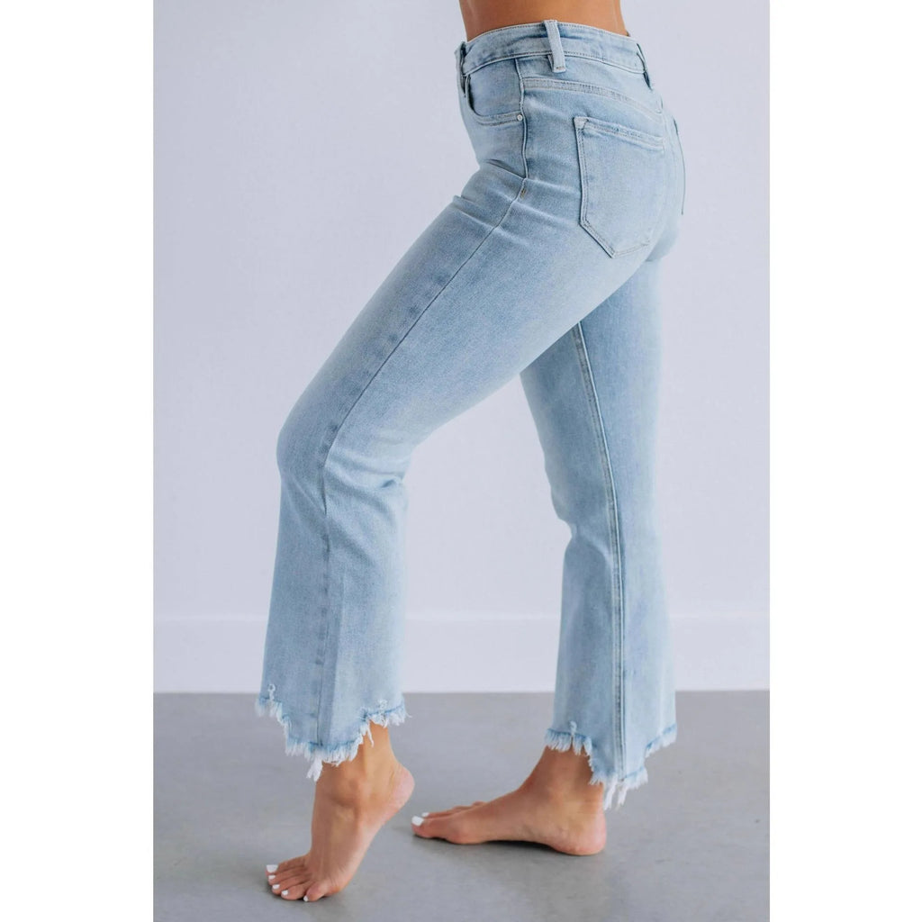 Solid colour women's denim trousers with hand-worn distressing on a hanger.