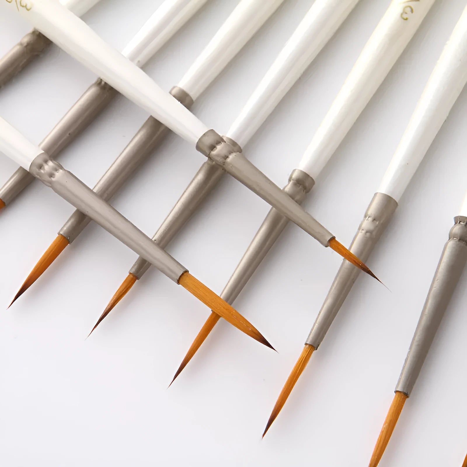 12 Pearl White artist brushes with nylon wool bristles and solid wood handles arranged by size.