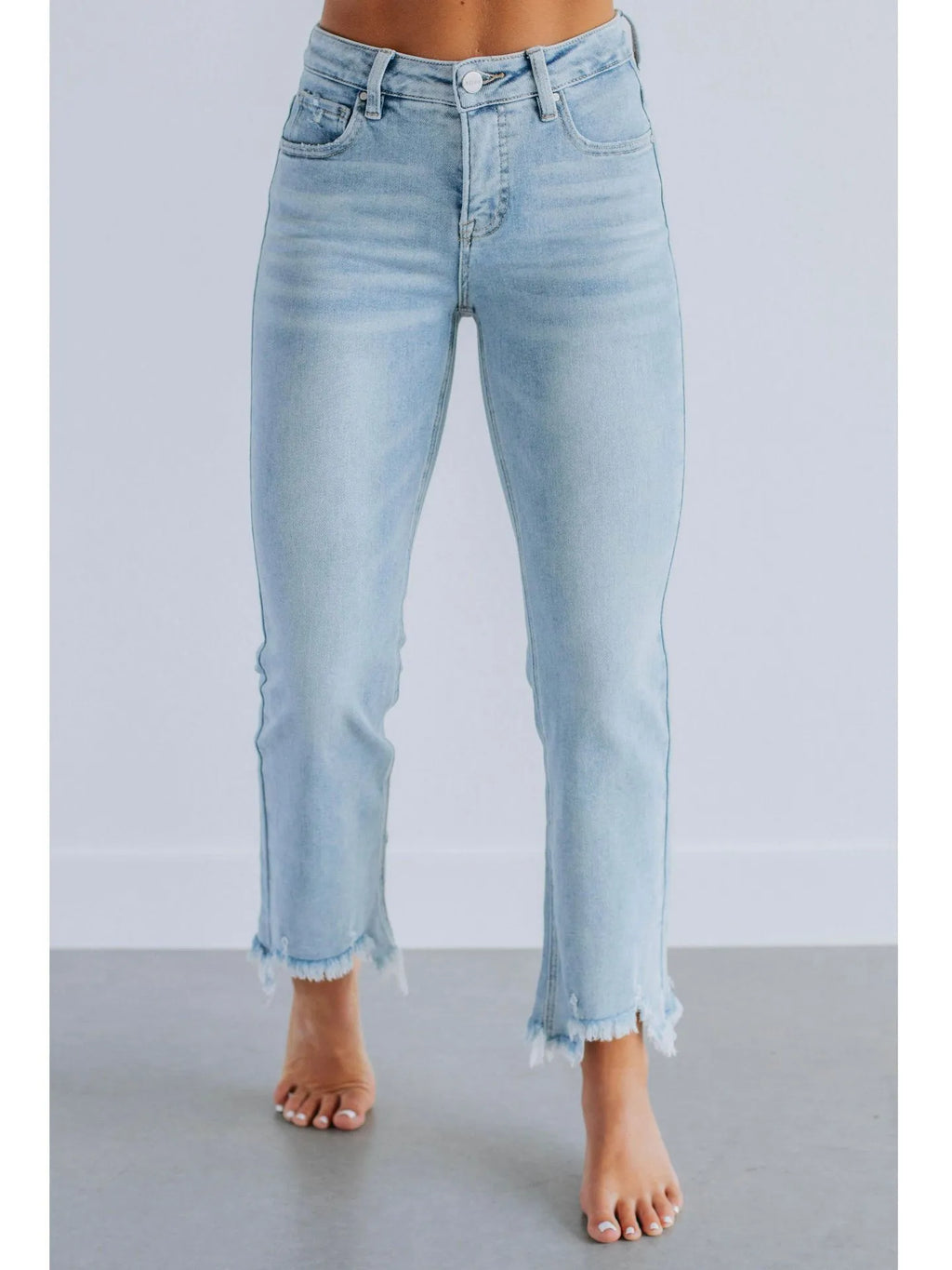 Solid colour women's denim trousers with hand-worn distressing on a hanger.