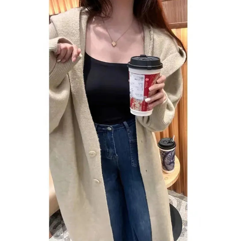 Women's long hooded knitted cardigan in oatmeal colour, showing below-knee length and loose fit.