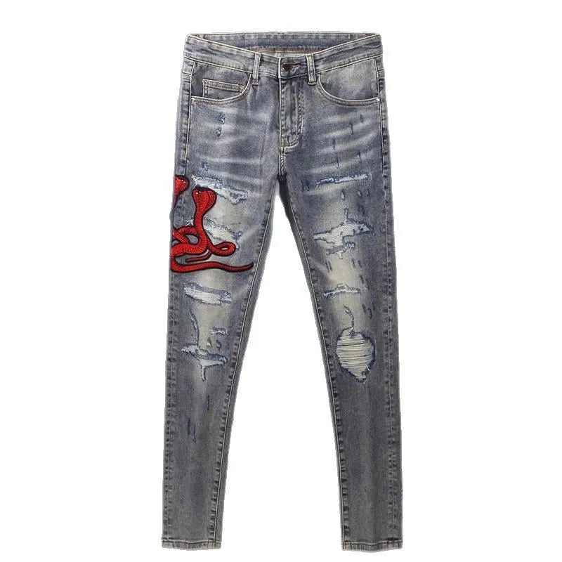 Men's slim fit jeans in old colour with distressed holes and embroidered patches on the legs.