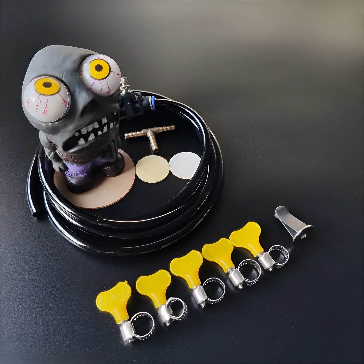 Turbo car blow-off valve ornament kit showing rubber doll, copper tube, pressure valve, and tubing on a car vent.