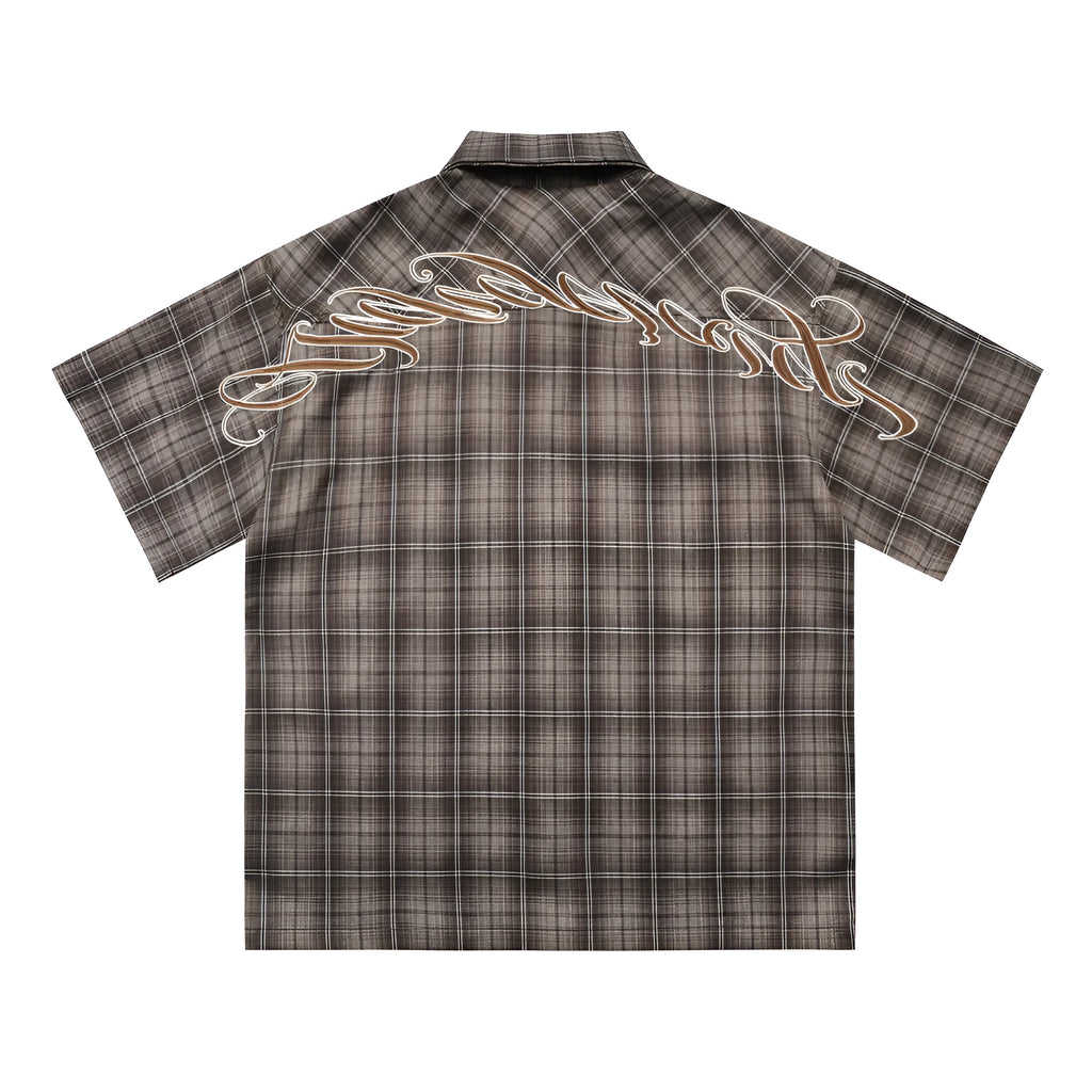 Man wearing a brown plaid short sleeve shirt with embroidery on the lapel