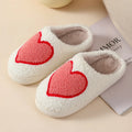 Women's plush home slippers in cartoon love style print with round toe and non-slip PVC sole.