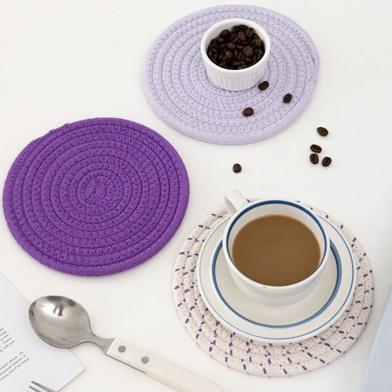 Set of three round grey cotton cord coaster placemats on a wooden table