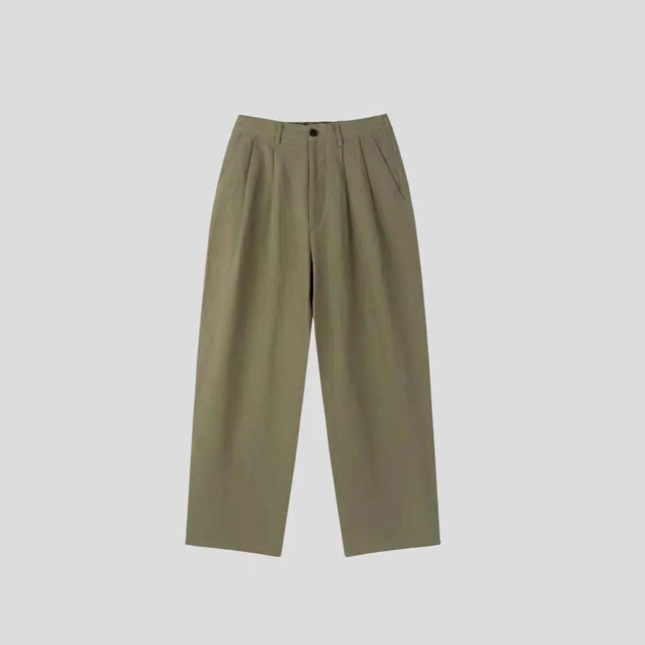 Men's apricot coloured loose-fit cotton linen blend trousers on a hanger, showing zip fly and mid-waist design.