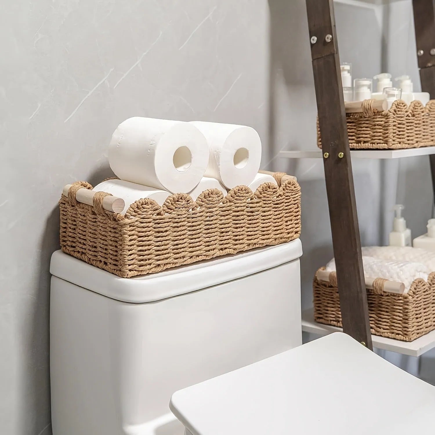 A woven paper storage basket in a neutral colour on a wooden desktop, holding remote controls and pens.
