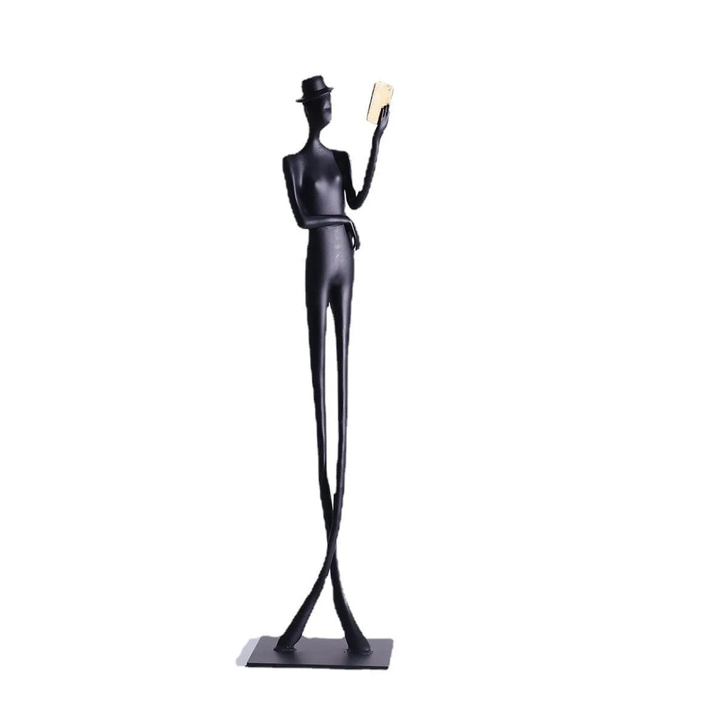 Black cast aluminium sculpture of a woman reading, modern minimalist style.