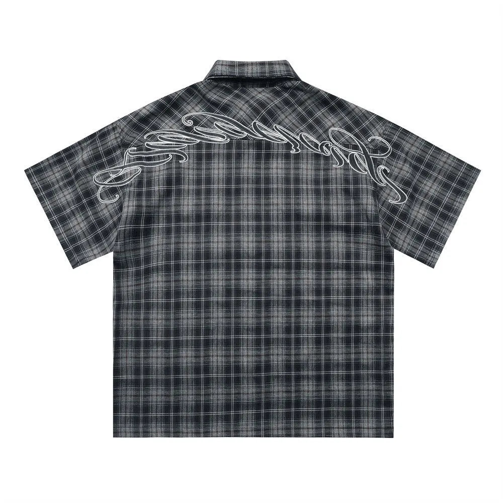 Man wearing a brown plaid short sleeve shirt with embroidery on the lapel