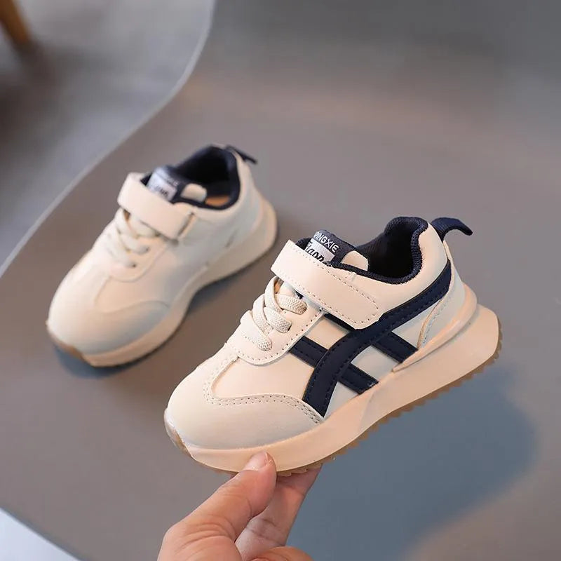 Children's white synthetic leather sneaker with a single Velcro strap and rubber sole.