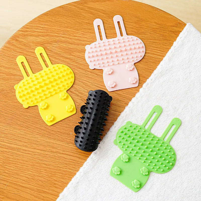 Silicone wall-mounted cat grooming brush with comb teeth and adjustable strap for table legs.