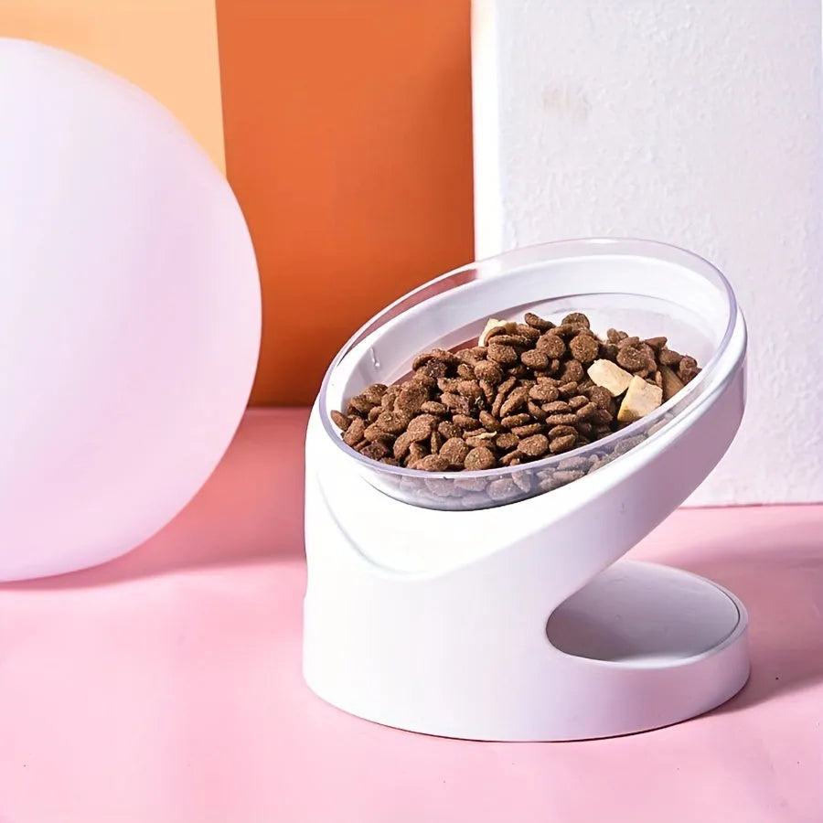 White clear plastic tilted cat food bowl on a flat surface.