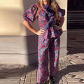 Women's floral print trousers suit with tie-neck blouse featuring puff sleeves and matching long trousers