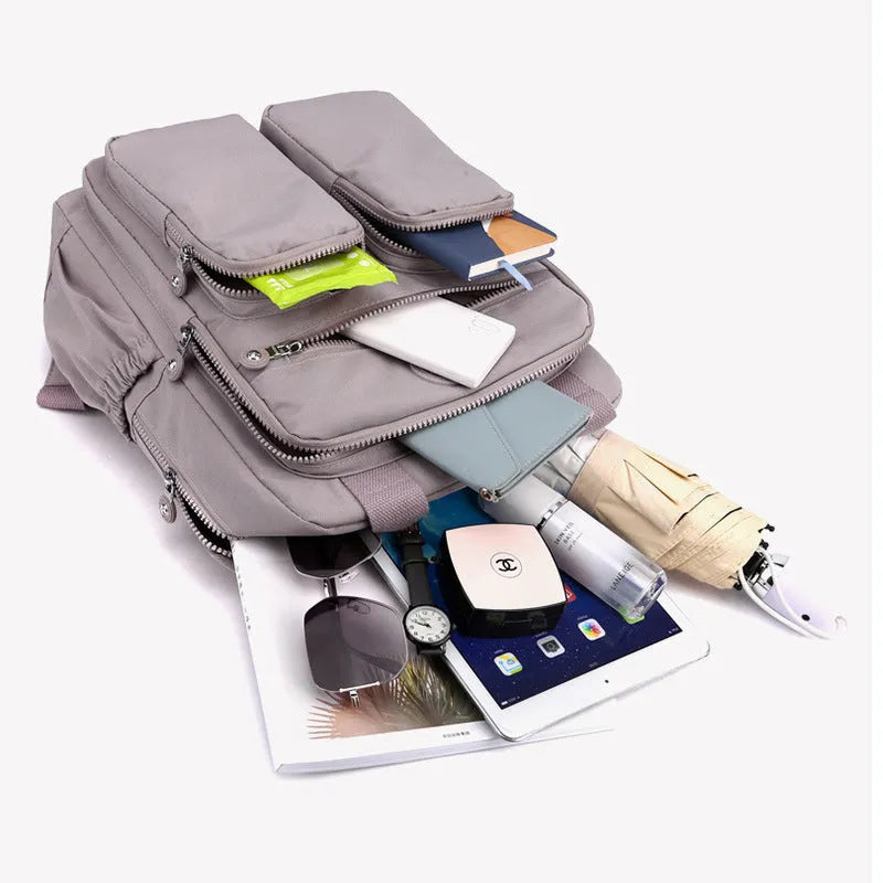 Women's large waterproof nylon travel backpack in lotus root purple showing internal laptop and camera compartments.